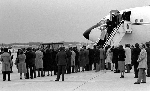 Image of Iran hostages disembarking from an airplane. There are several people waiting for them on the tarmac