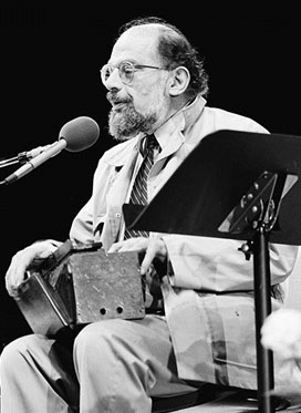 Image of Allen Ginsberg seated holding a box on his lap