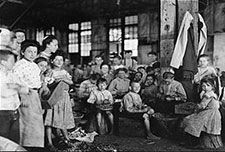 Very young children, mostly under ten years old, stringing beans in a factory near Baltimore, MD.